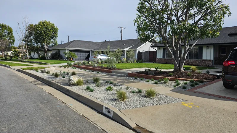 Updated front yard with new plants, accent rocks, and white river rock