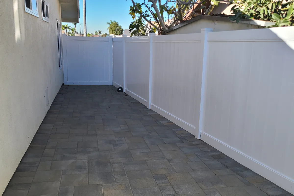 Huntington Beach backyard after Belgard paver installation and white vinyl fencing
